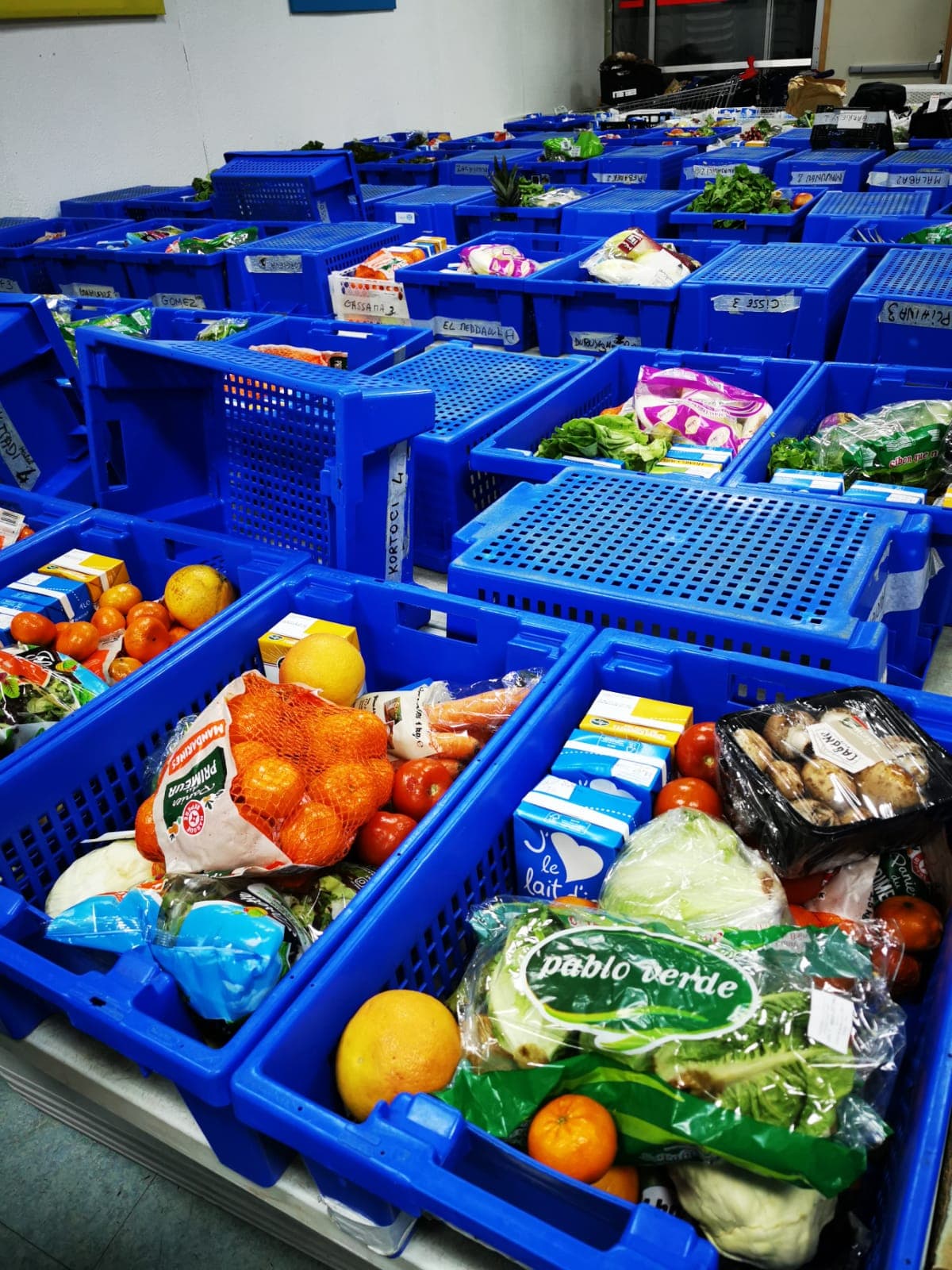 Vue d'ensemble de la salle de distribution — caisses bleues remplies de légumes frais